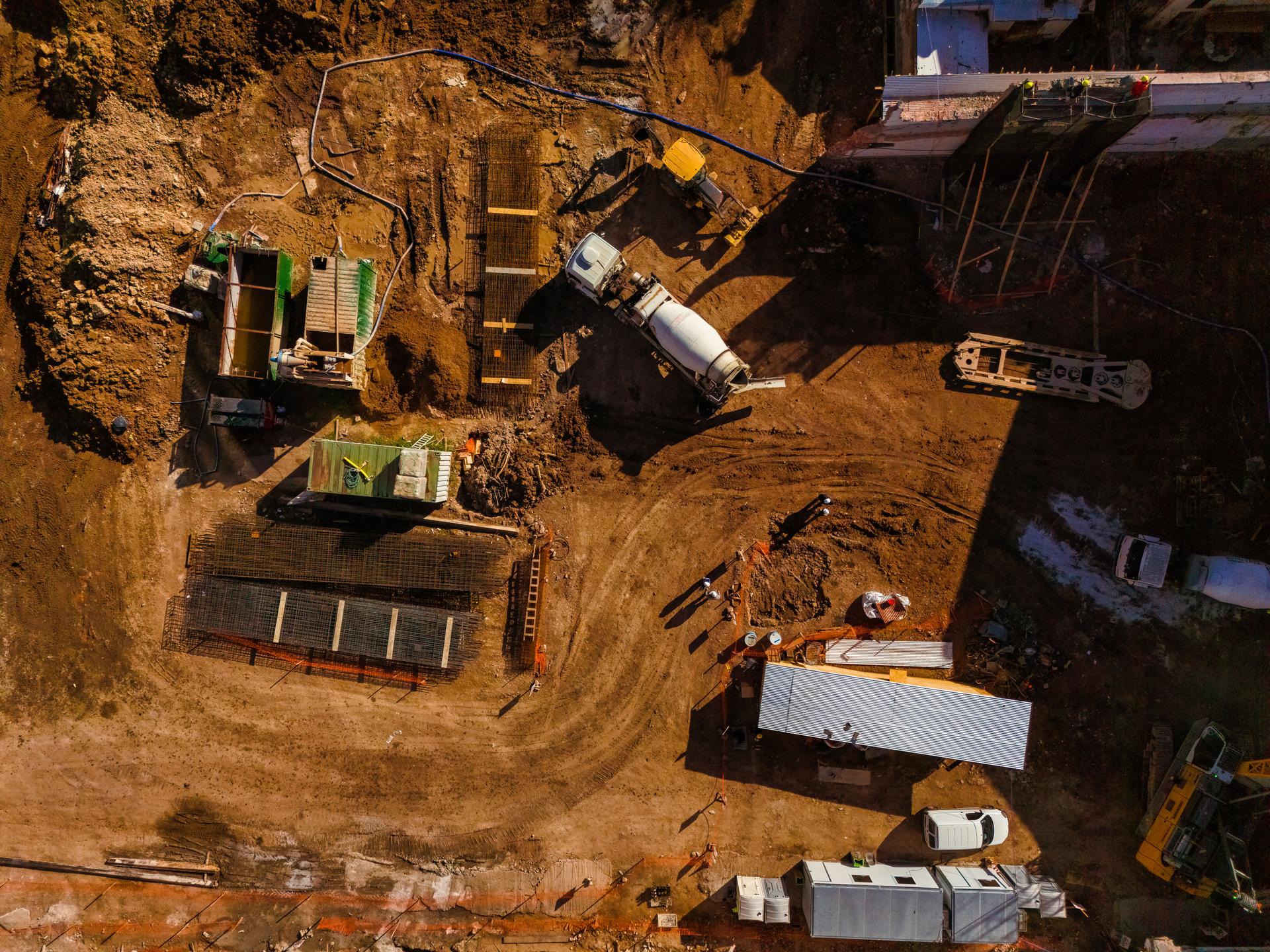 Top aerial view of a construction site with cement mixer truck, machinery and workers