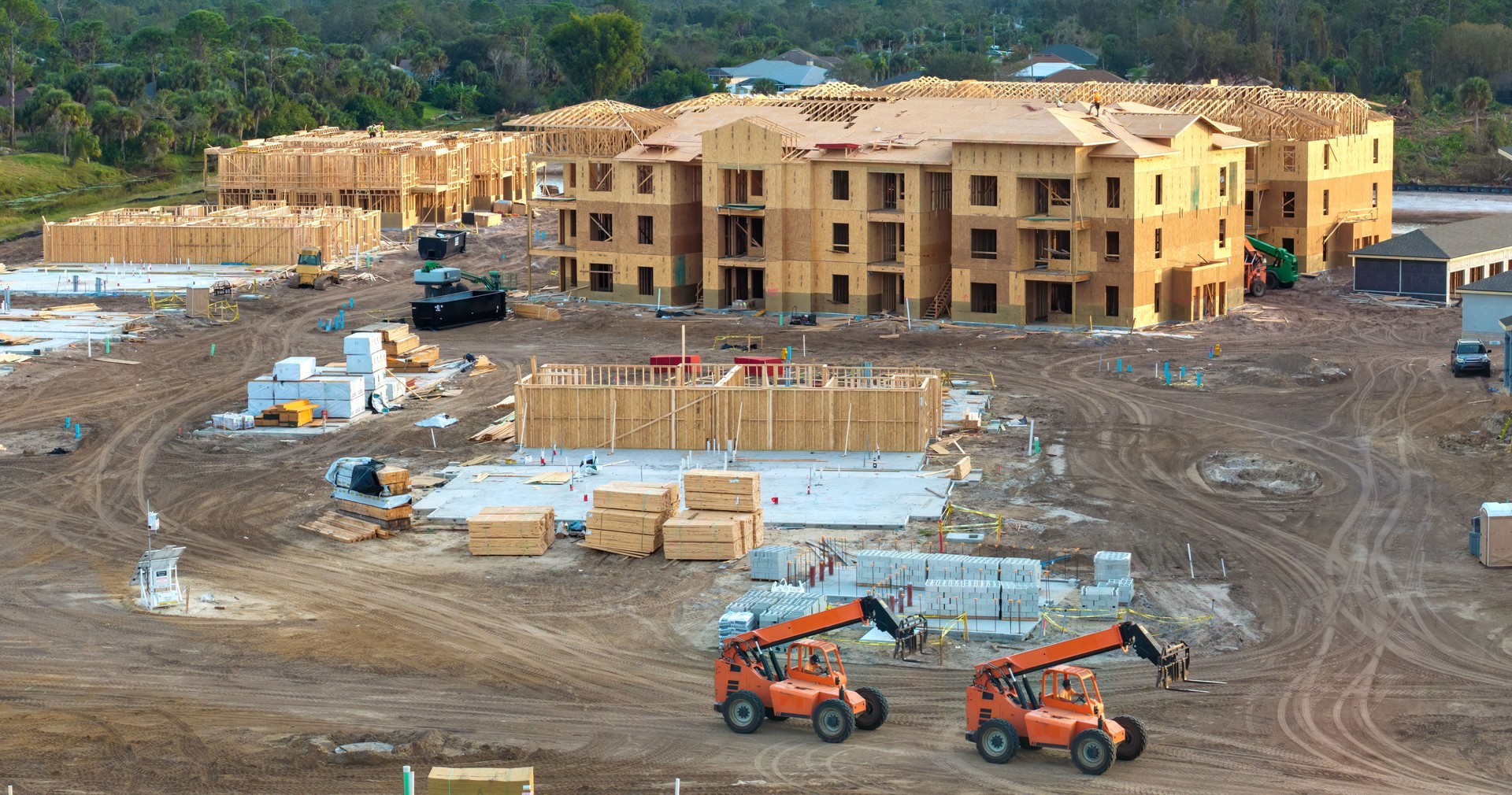 Development of residential housing in American suburbs. Unfinished frames of apartment condos with wooden roof beams under construction. Real estate market in the USA