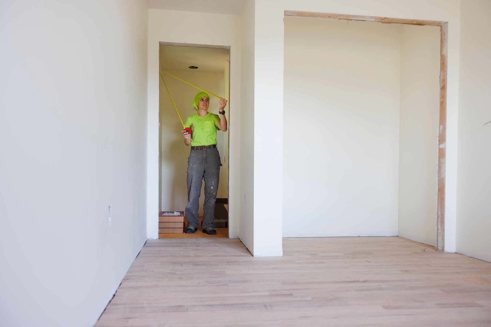 Contractor inspects doorway dimensions in partially renovated room. Property assessment for residential remodeling project.
